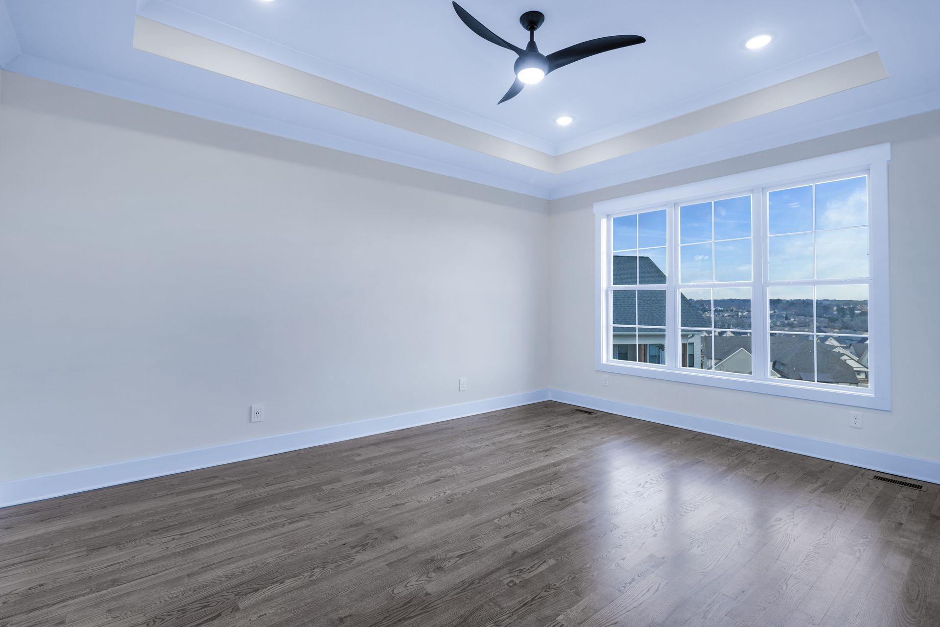 an empty room with hardwood floors and a ceiling fan .