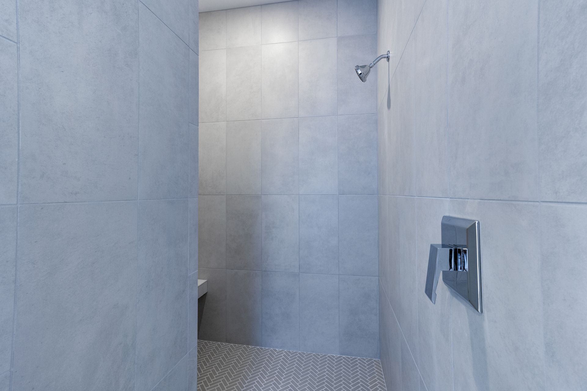 a walk in shower with gray tiles and a shower head .
