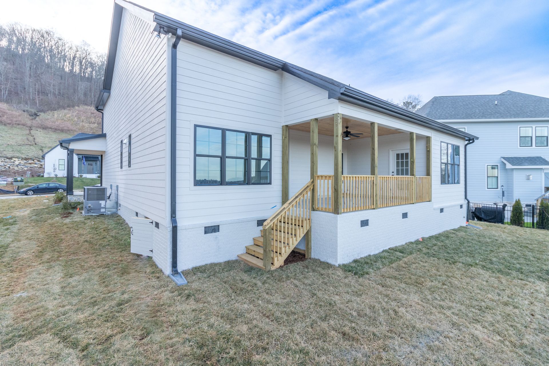 the back of a white house with a porch and stairs .