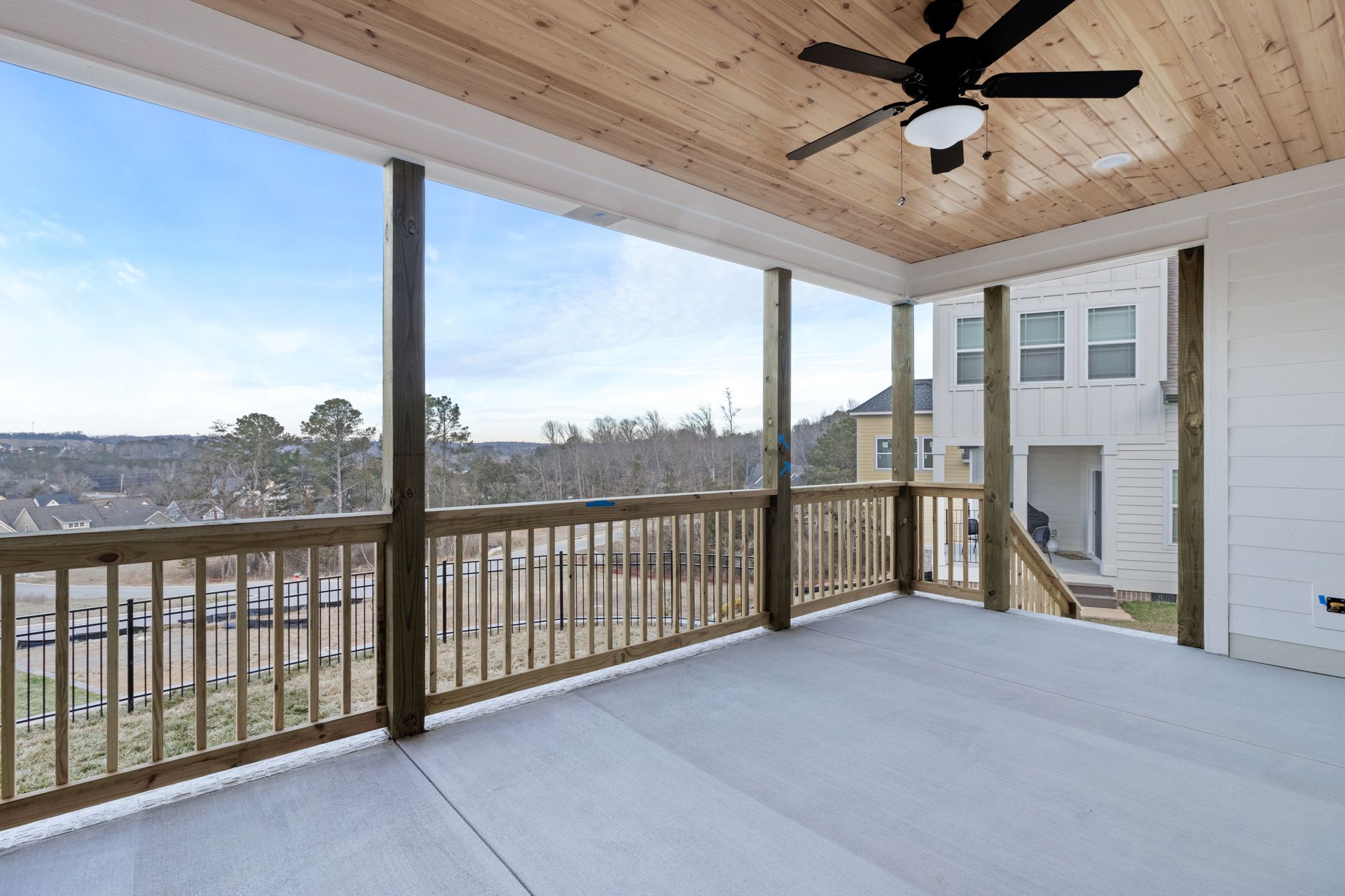 a screened in porch with a wooden railing and a ceiling fan .
