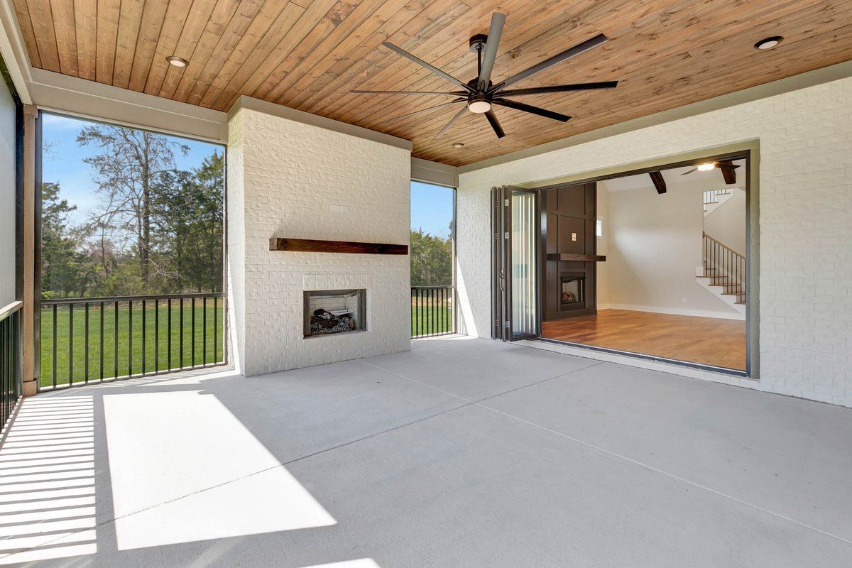 A screened in porch with a fireplace and a ceiling fan