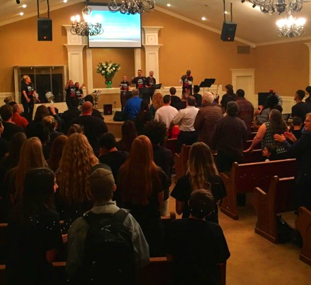 A large group of people are sitting in a church watching a presentation