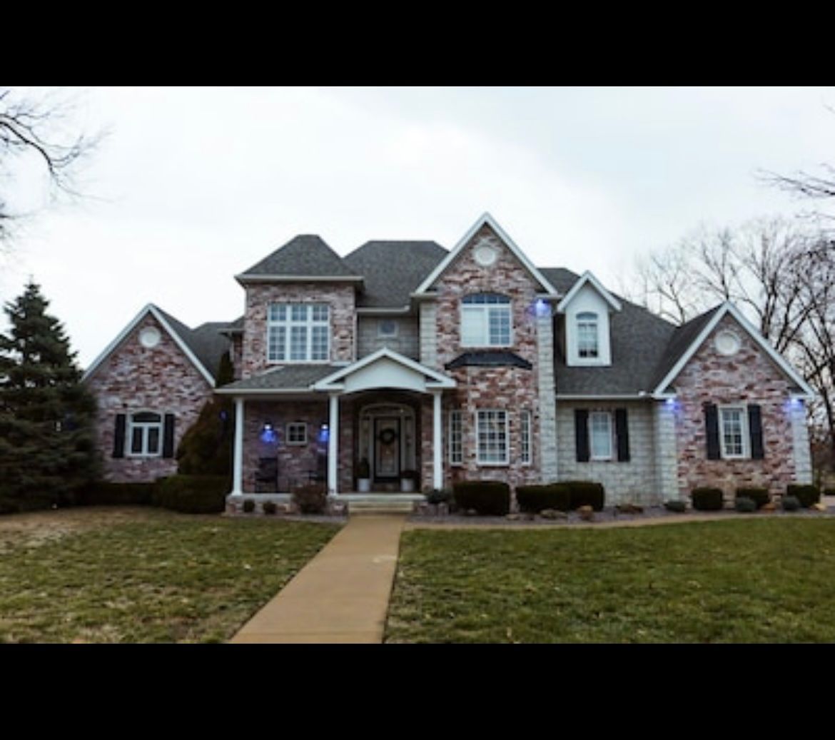 A large brick house with a gray roof and black shutters