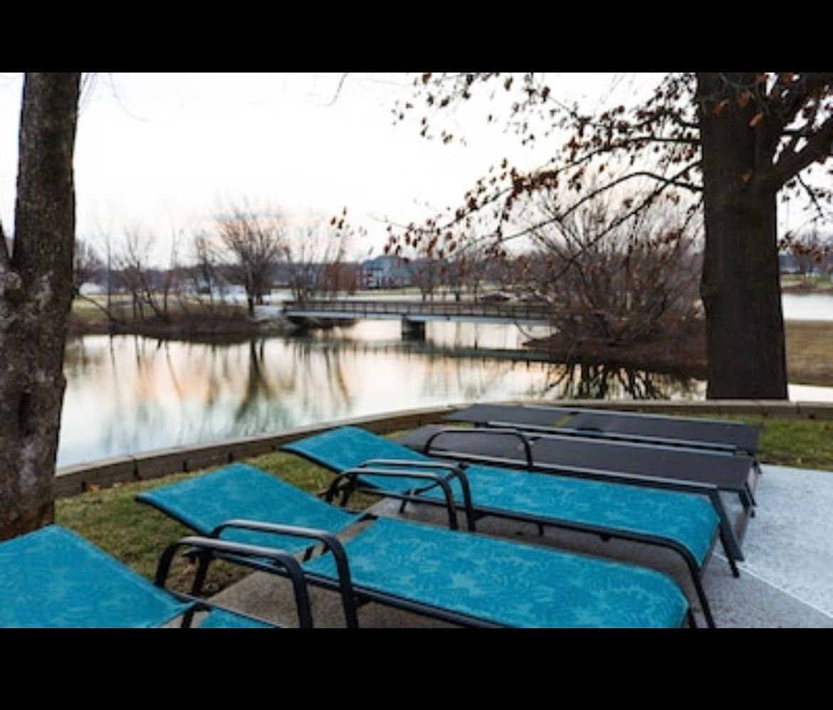 A row of blue lounge chairs sit in front of a body of water