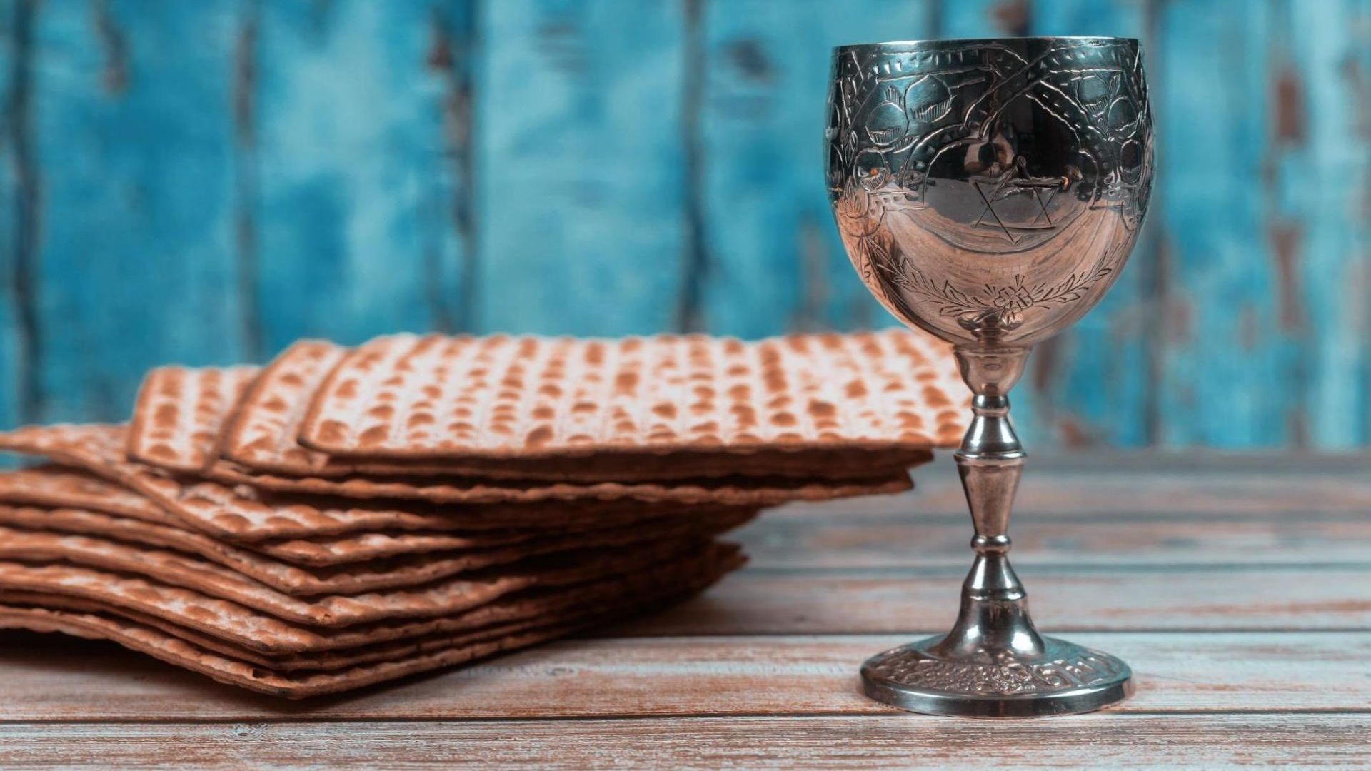 A stack of matzah and a glass of wine on a wooden table.