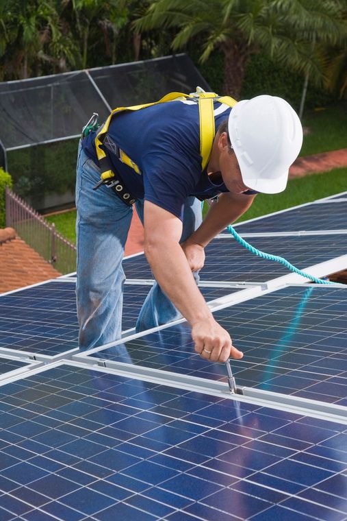 Un uomo che indossa un casco sta lavorando su un pannello solare