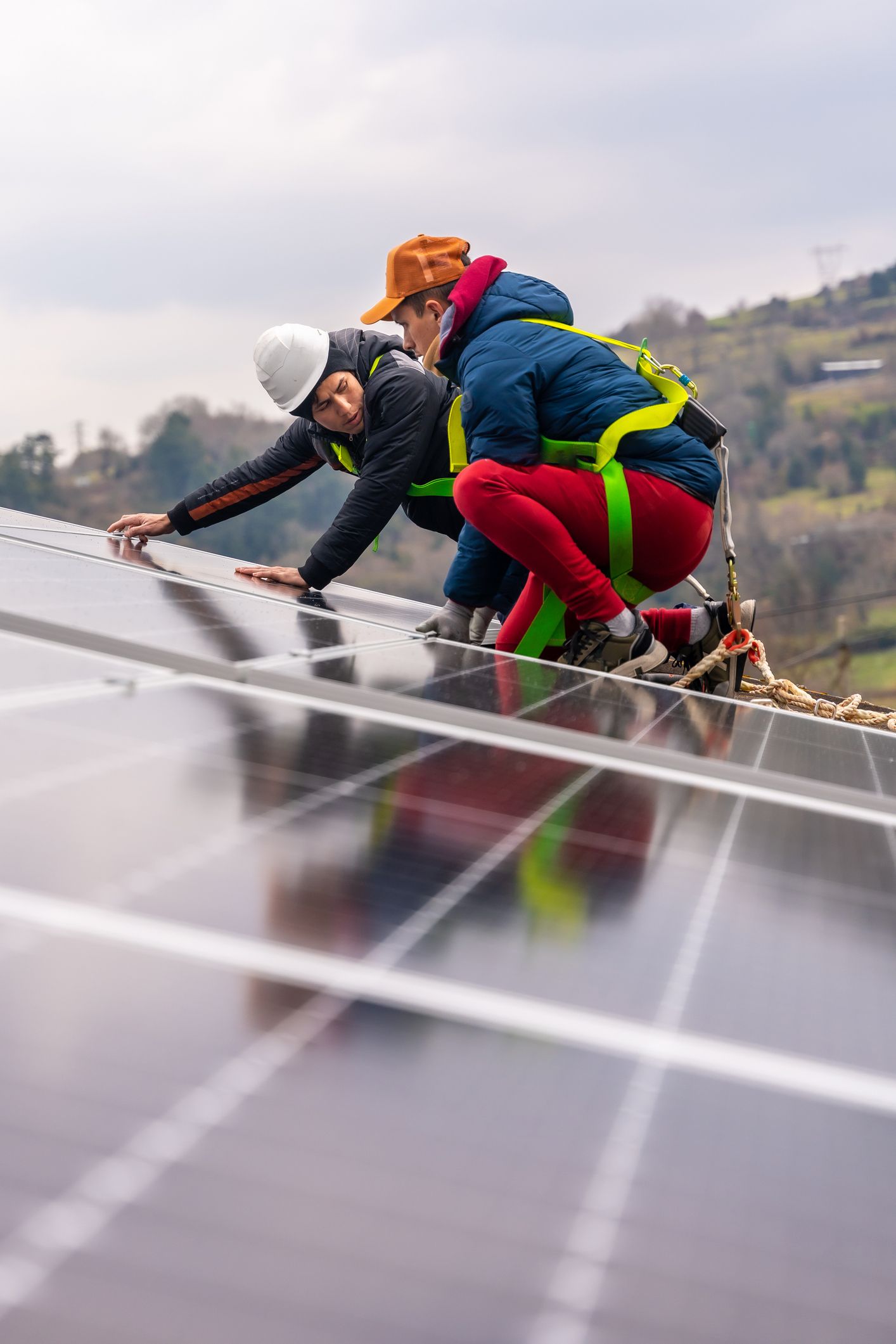 Due uomini stanno lavorando su un pannello solare in cima a un tetto.