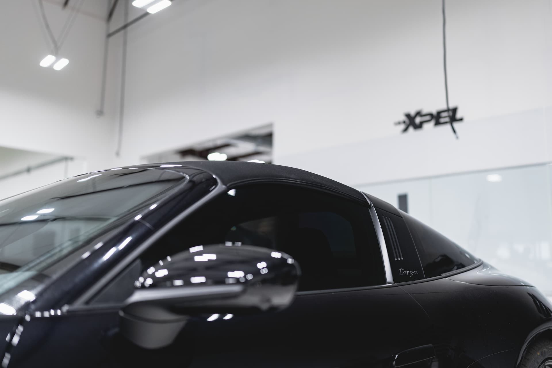 Black Porsche Targa roof and side mirror, indoors with 