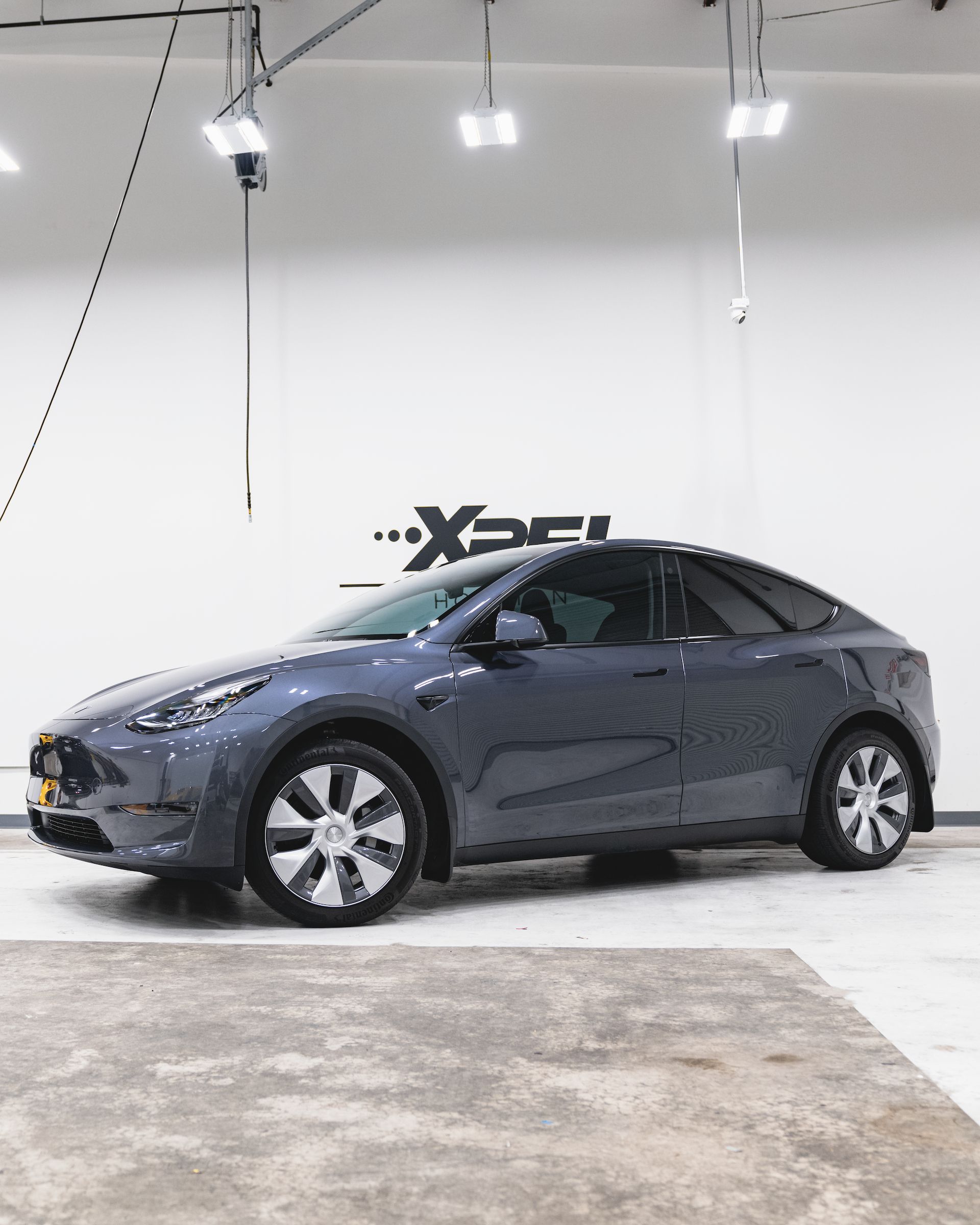 Gray Tesla Model Y car in a brightly lit studio.