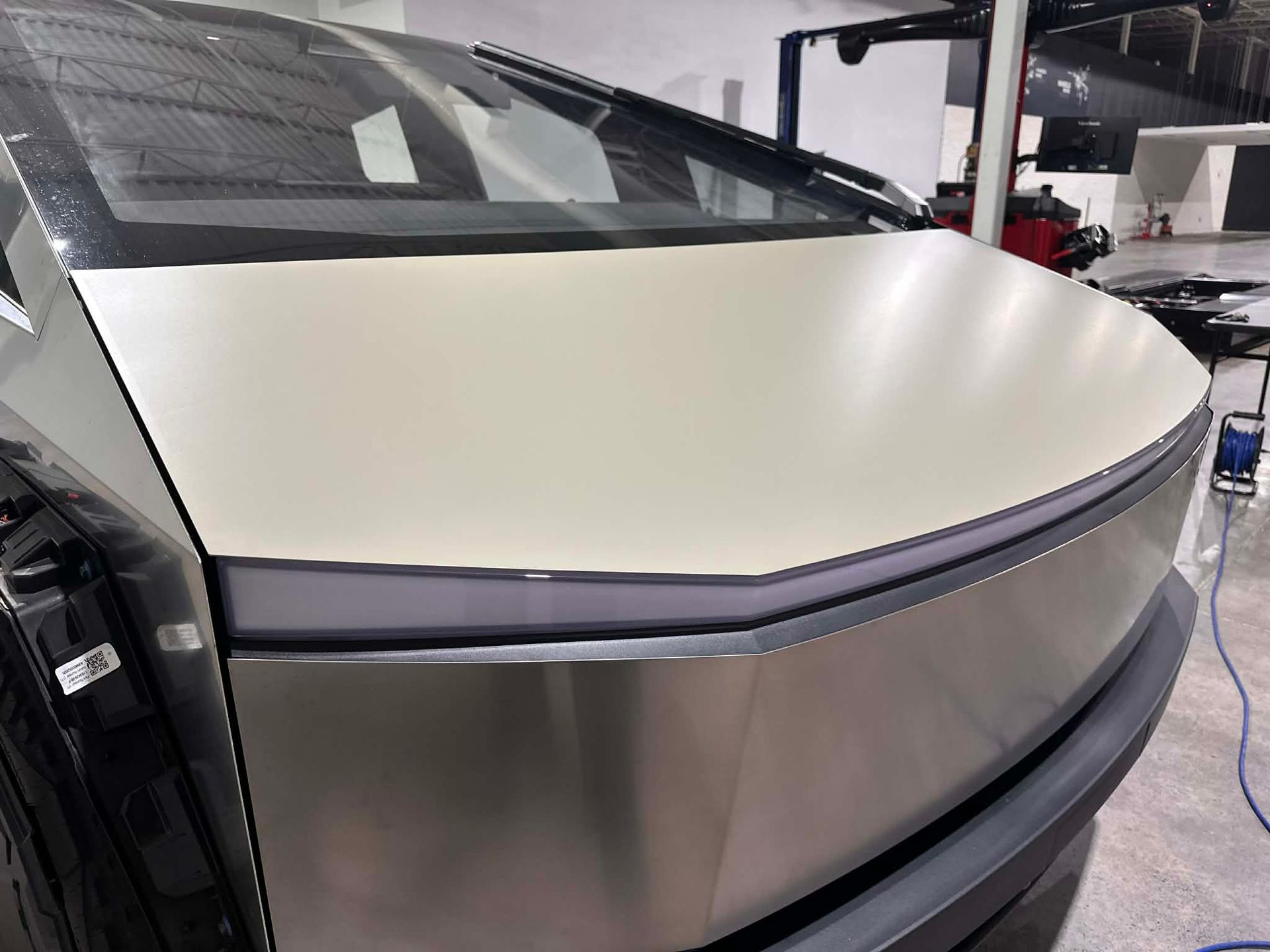 Rear of a Tesla Cybertruck with a matte white wrap on the rear hatch, over the stainless steel body.