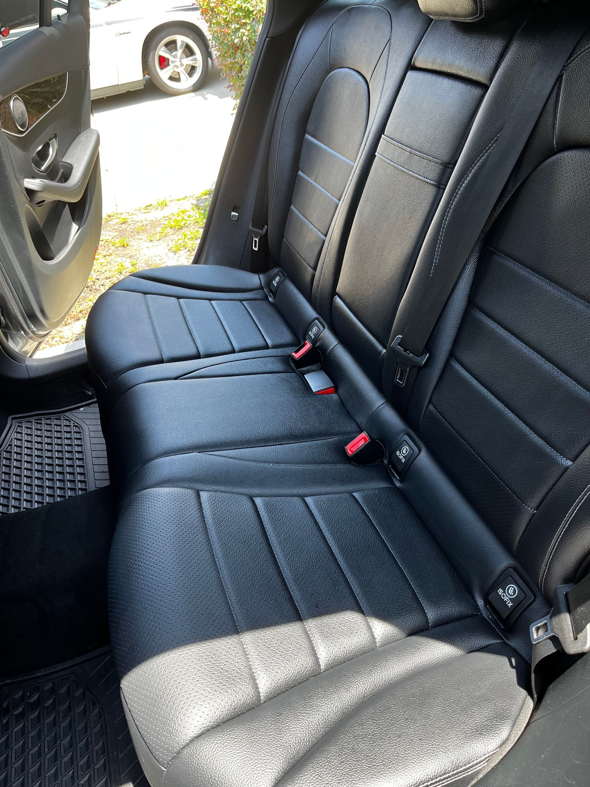 Black leather car back seat with a wet appearance, possibly recently cleaned.