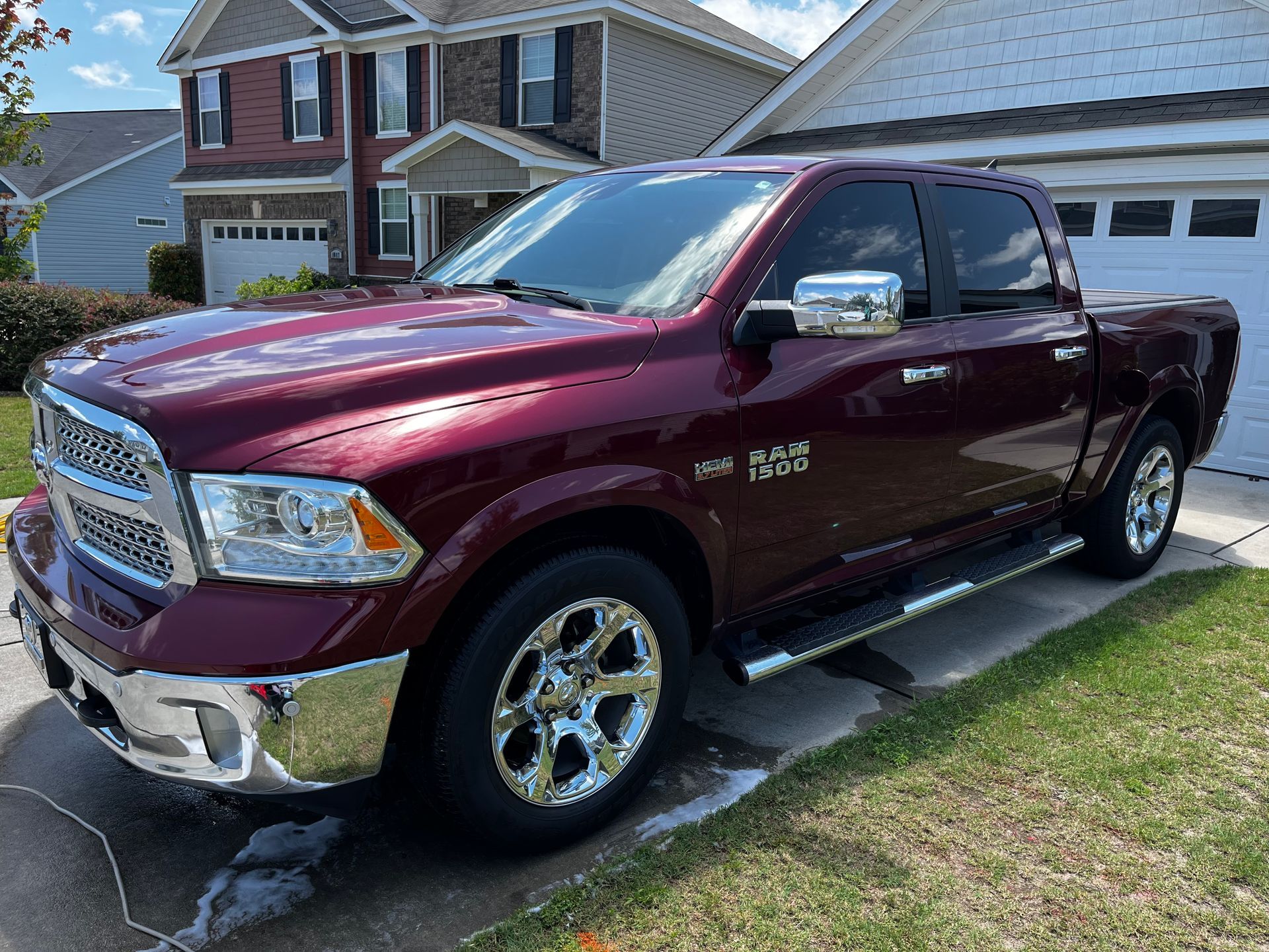 Burgundy Ram pickup truck parked on a driveway in front of a house.