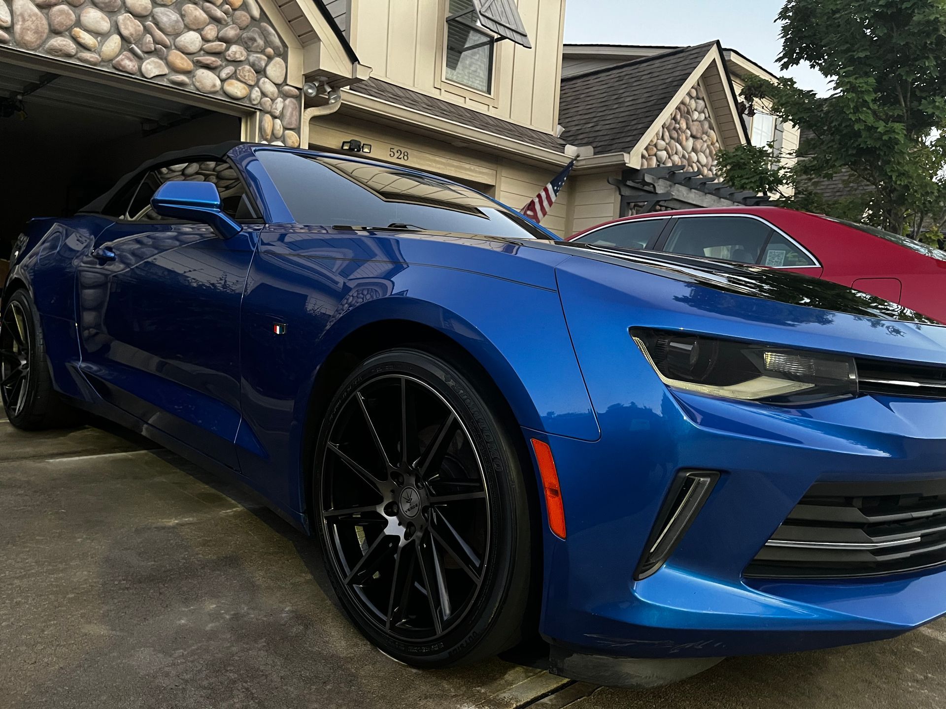 Blue sports car parked in a driveway, with black wheels.