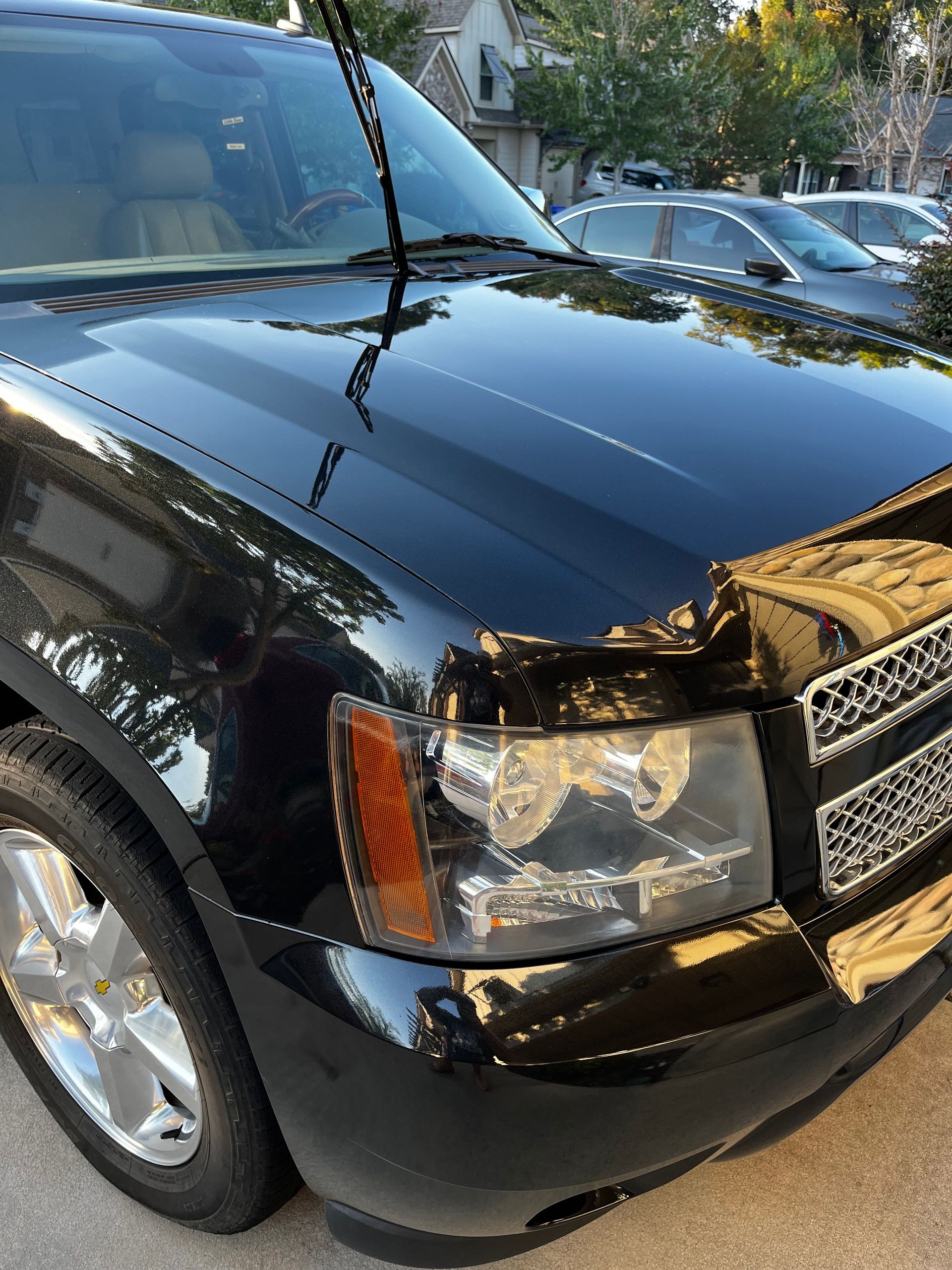 Black SUV with shiny hood, headlight, and grill. Silver wheels.