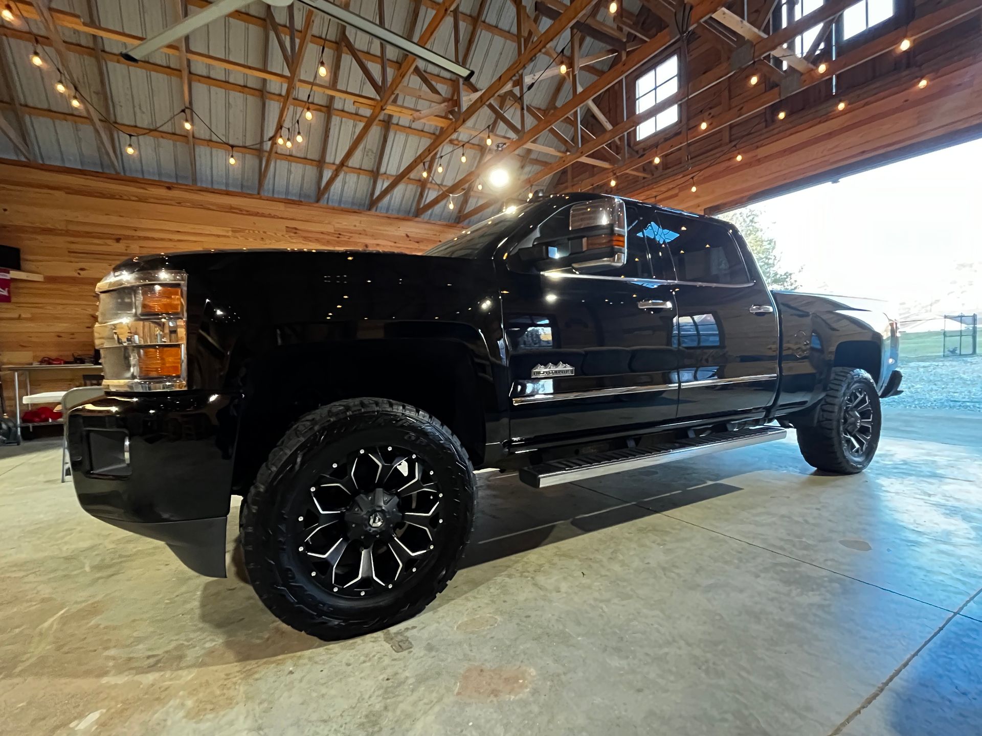 Black pickup truck parked inside a building with a wood ceiling.