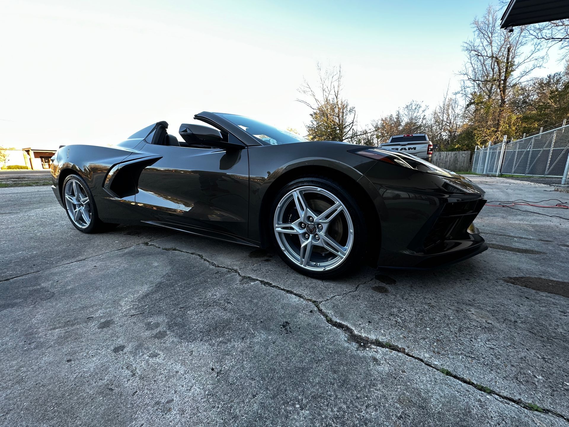 Dark gray convertible sports car parked on a concrete surface.