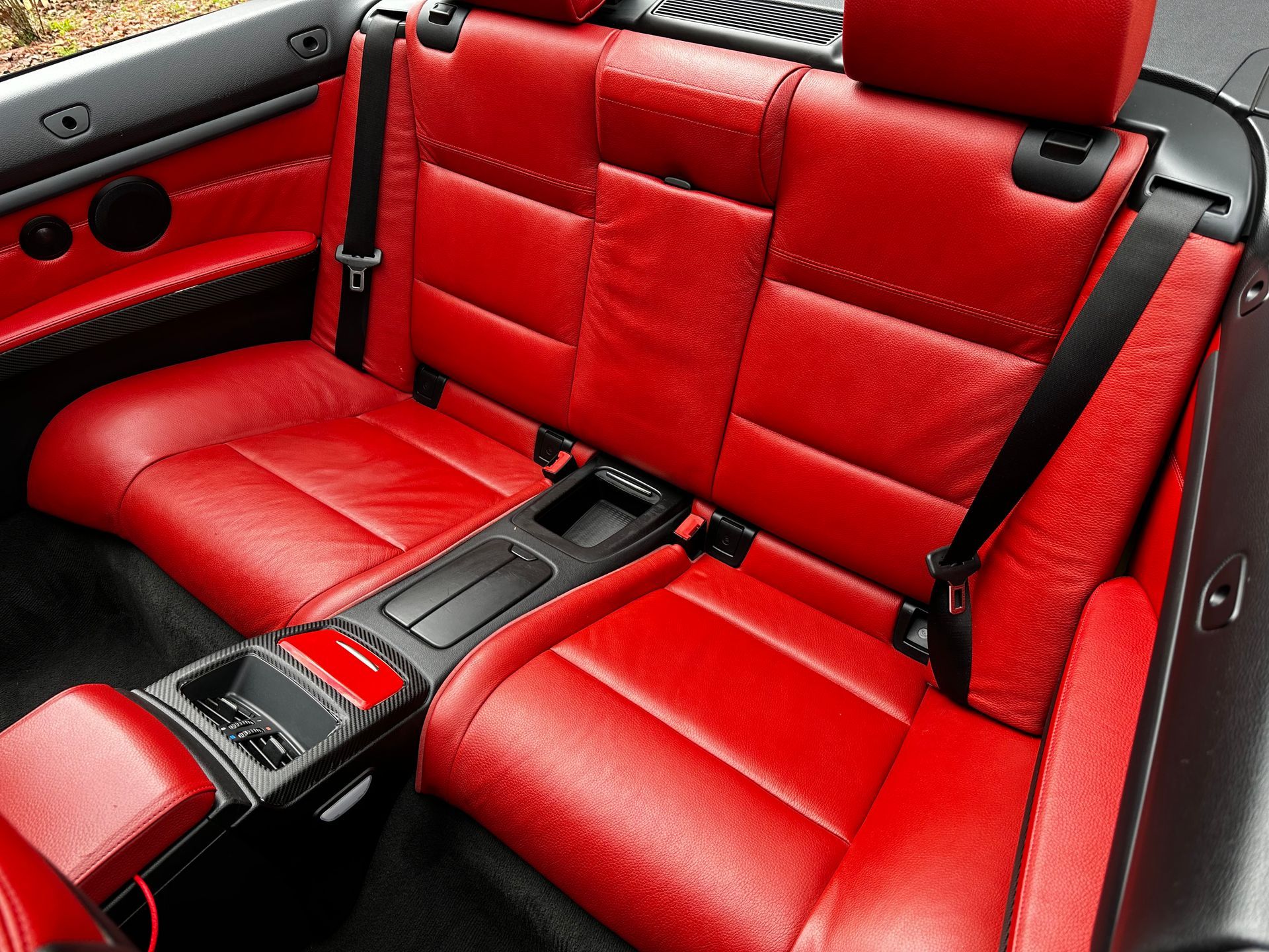 Red leather car backseat with a black console.
