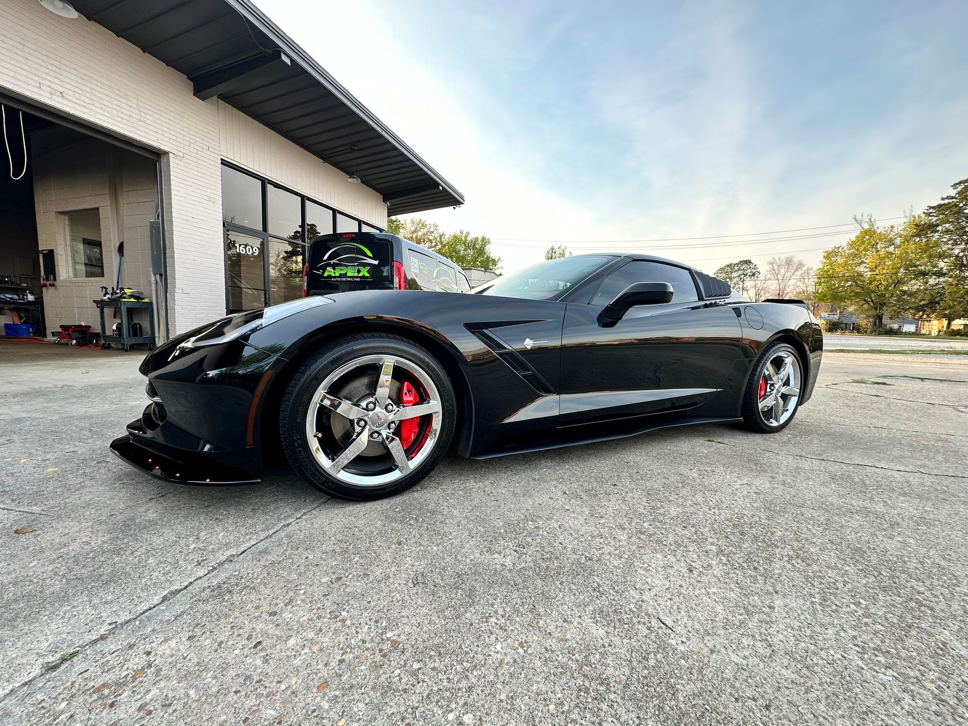 Black Corvette sports car with red brake calipers parked outside a building.