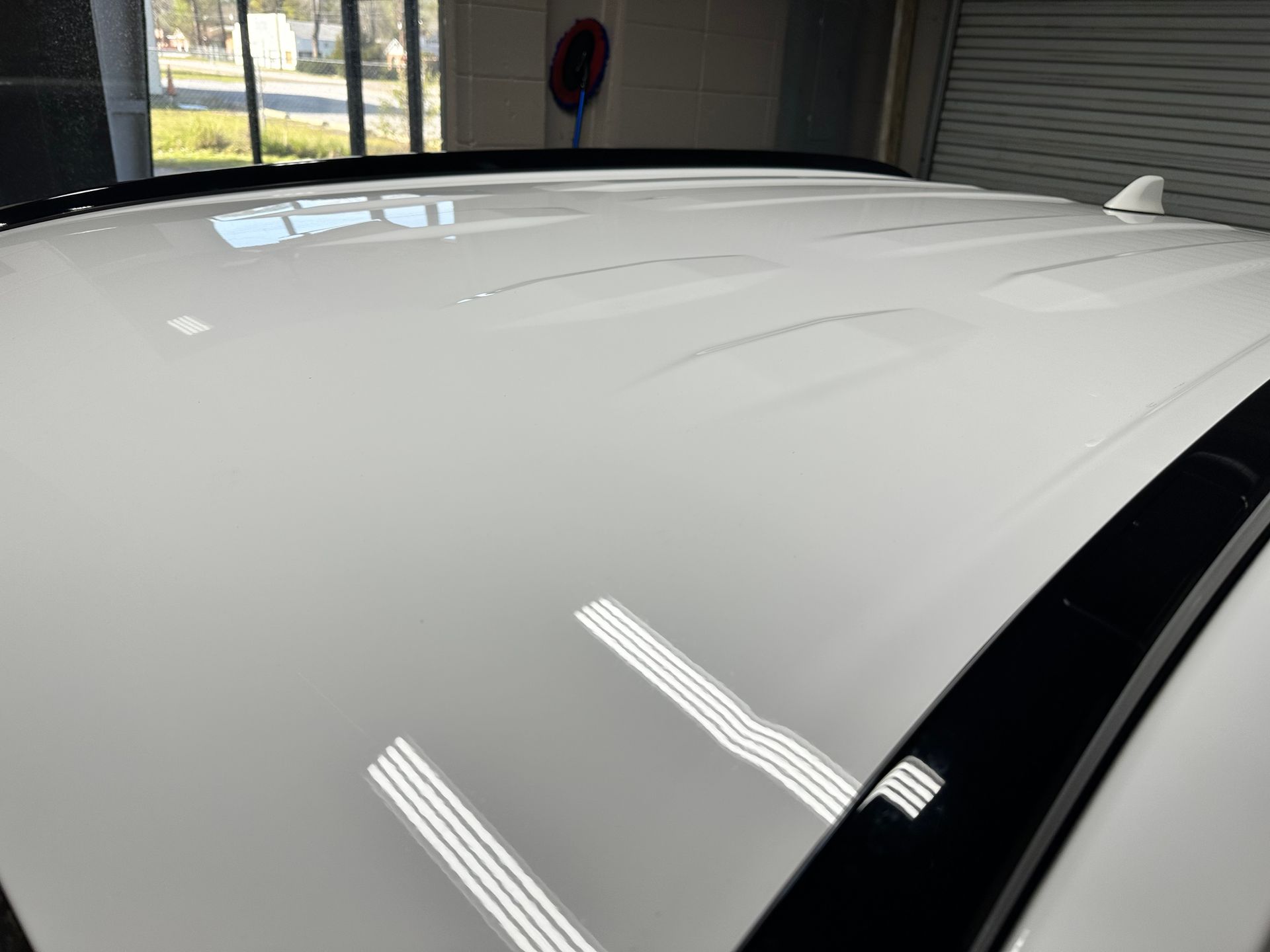 White car roof with shiny finish, reflecting interior lights.
