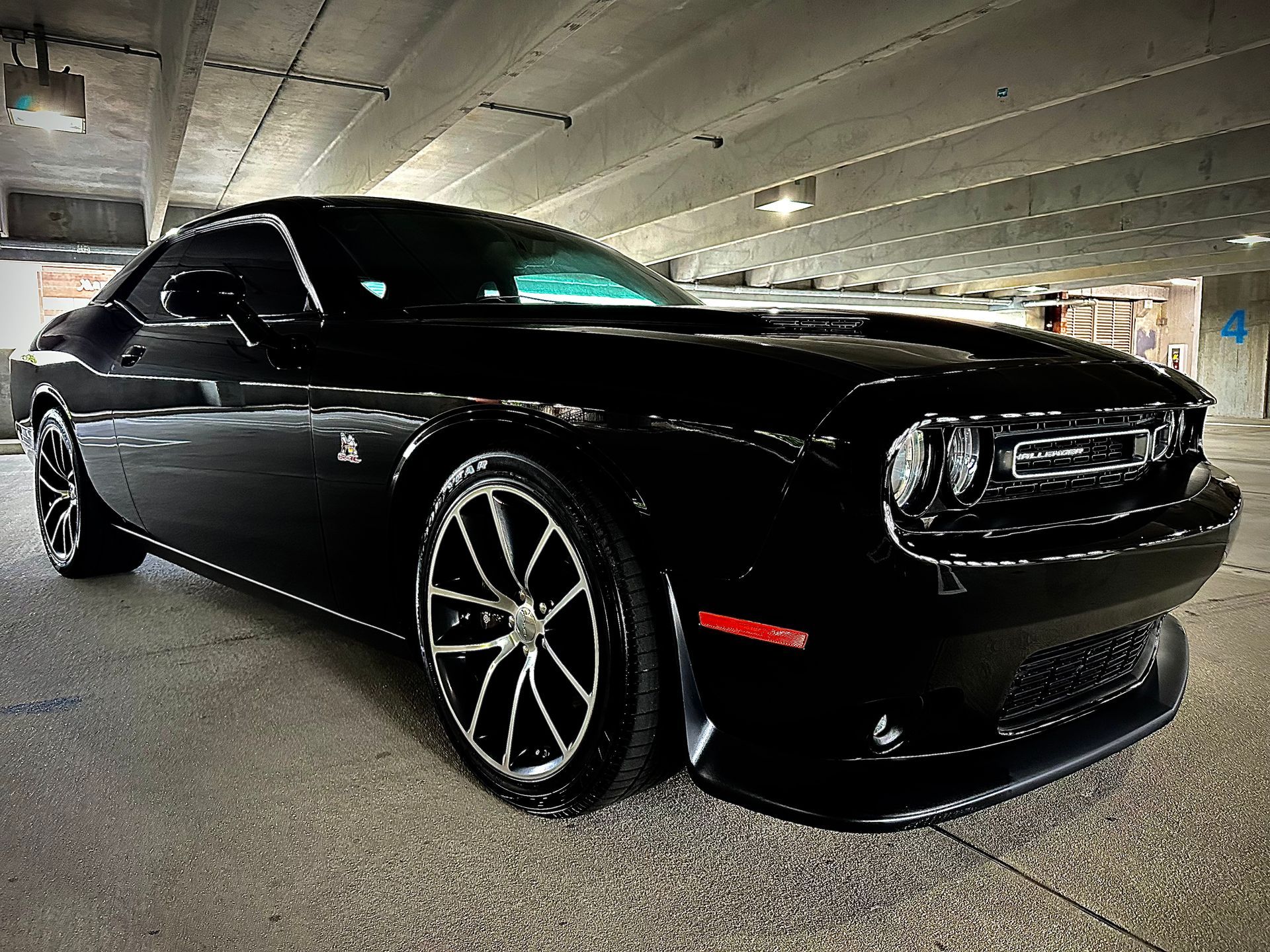 Black Dodge Challenger parked in a parking garage.