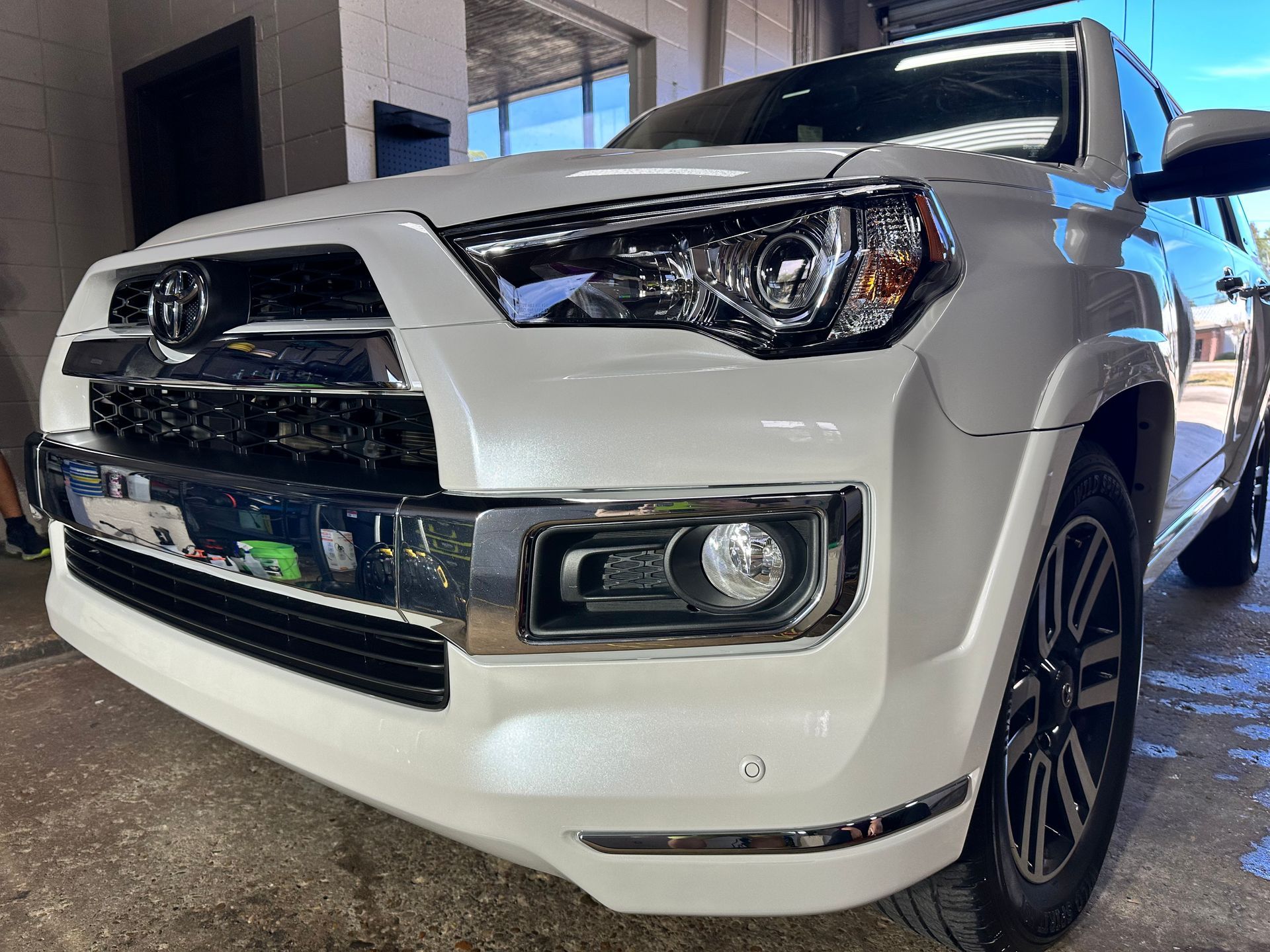 White Toyota 4Runner SUV, close-up of front end, chrome accents, black grill, parked outside.