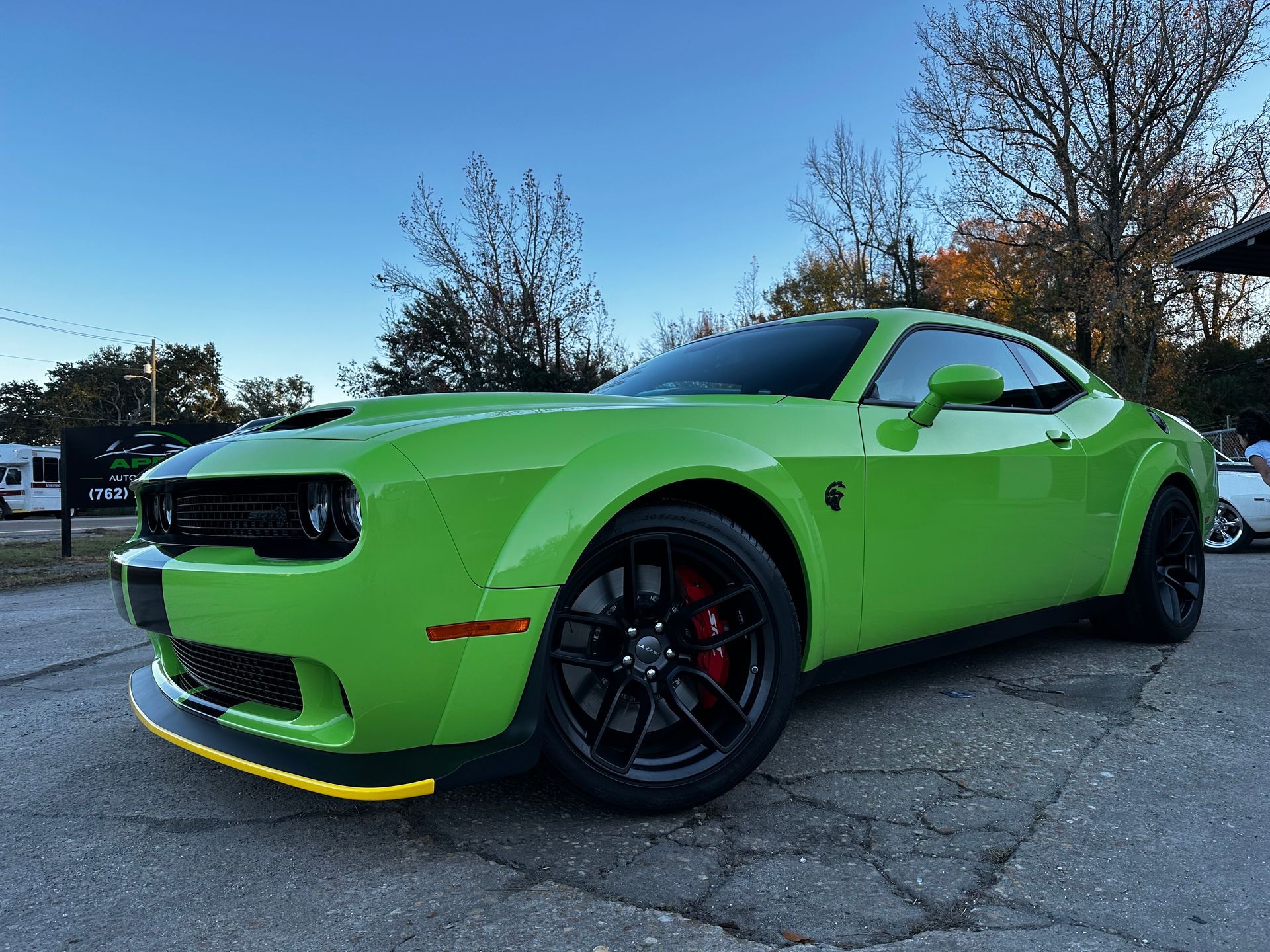 Green Dodge Challenger with black wheels and red brake calipers parked outside.