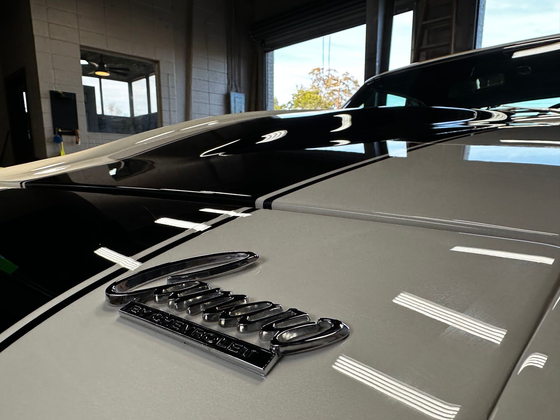 Close-up of a white car hood with a black racing stripe and chrome 