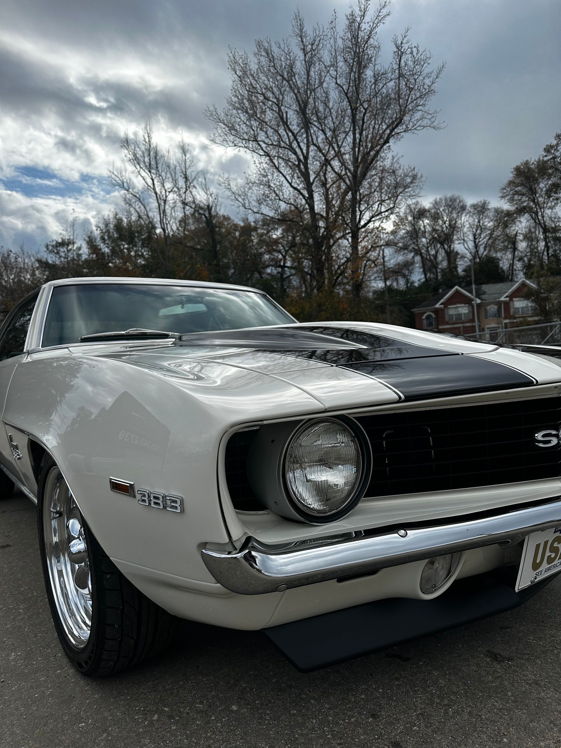 White 1969 Chevrolet Camaro SS with black racing stripes parked on asphalt.