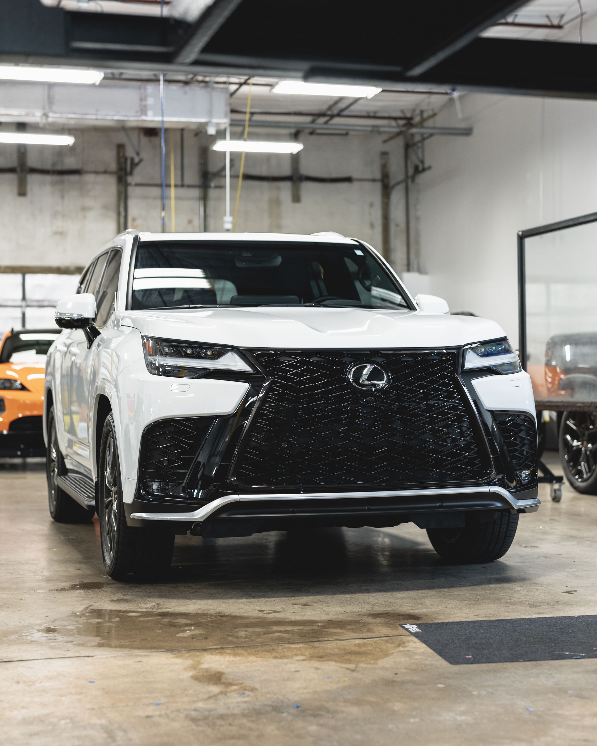 White Lexus SUV parked inside a garage, black grille, gray concrete floor.