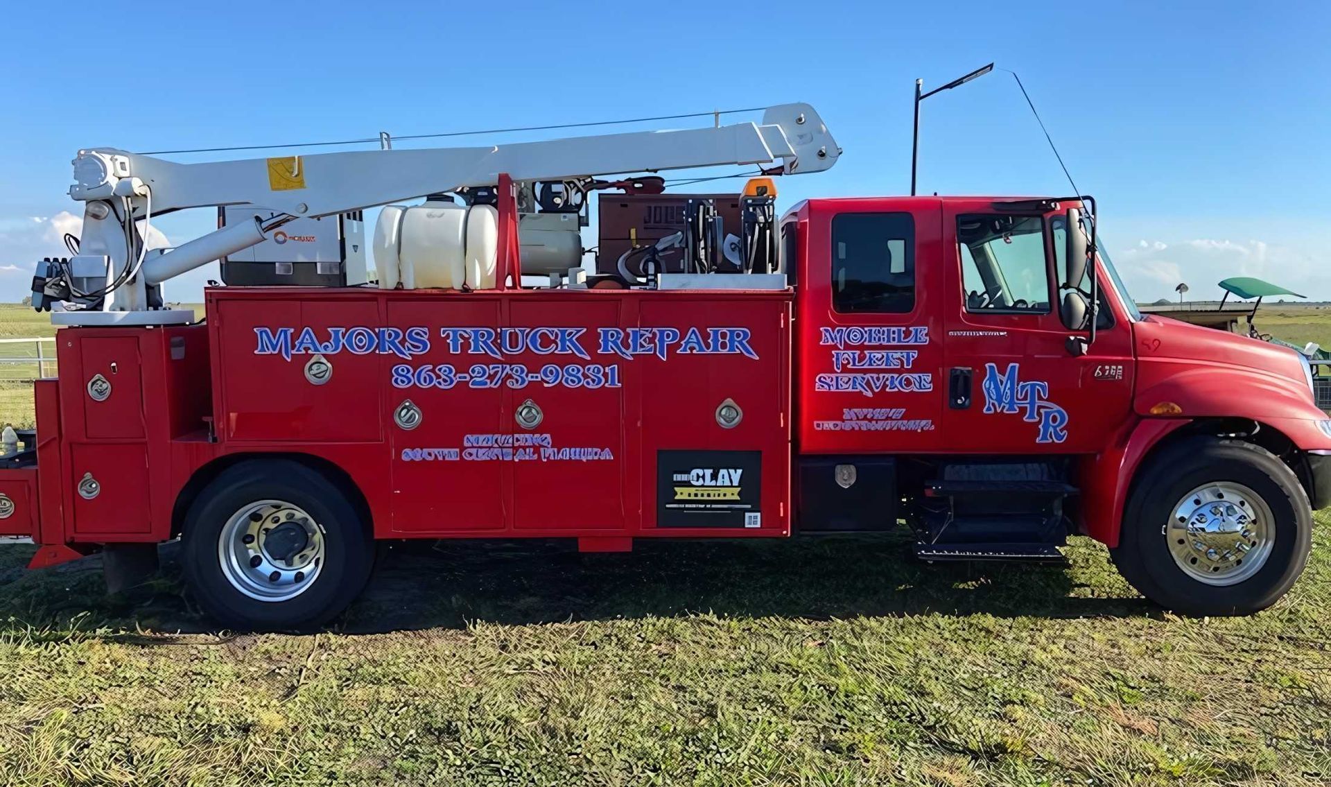 A red utility truck is parked in a grassy field