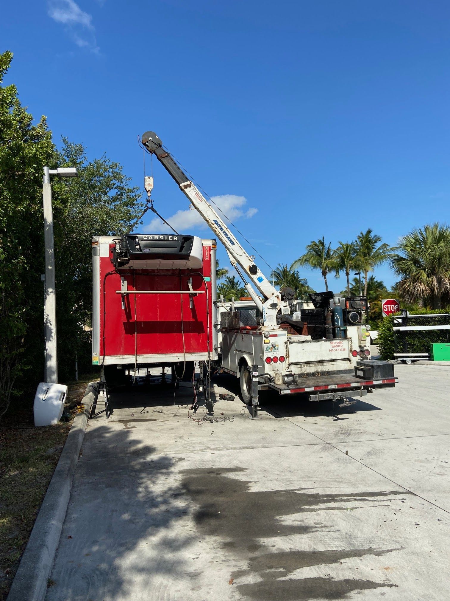 A red truck is being lifted by a crane in a parking lot.