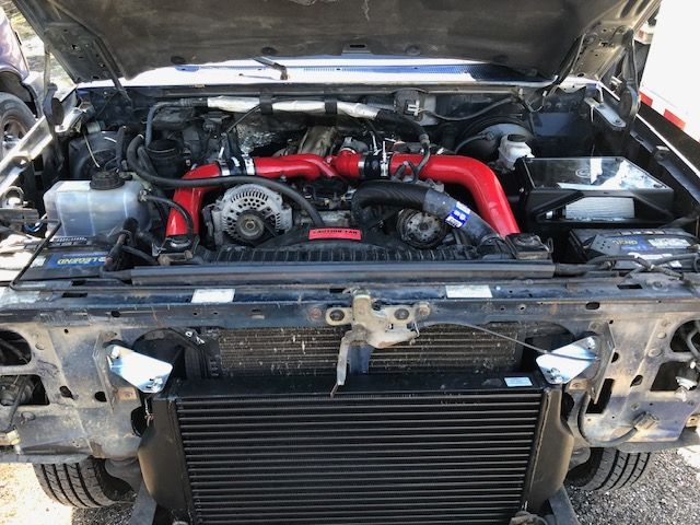 Ford truck engine bay with red piping, black intercooler, and various engine components.