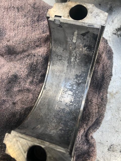 Worn engine bearing with discolored surfaces, possibly indicating wear or damage.