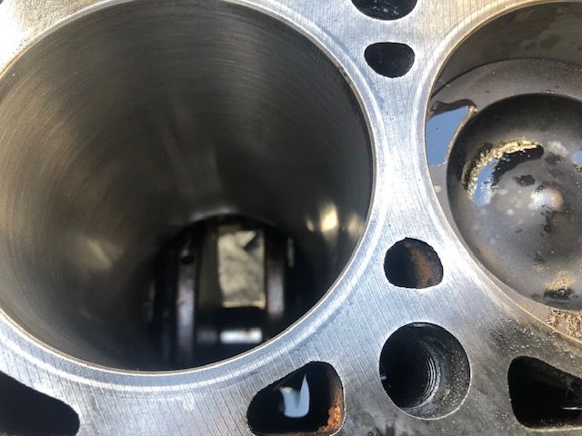 Interior view of an engine cylinder, showing the piston and connecting rod inside the cylinder bore.