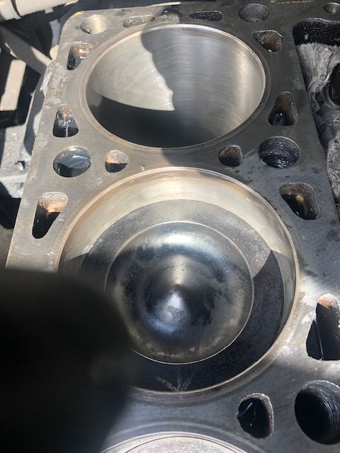 Close-up of a disassembled engine block showing two cylinder bores. One has a piston inside.