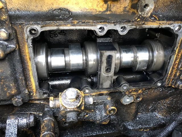 Open engine compartment with a camshaft visible, coated in oil.