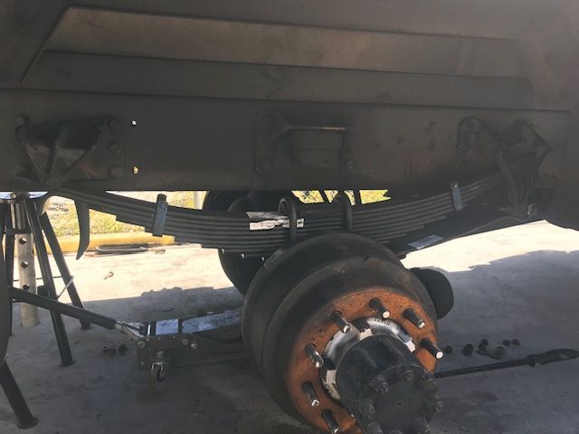 Truck's undercarriage with leaf spring suspension, rear axle, and supports. The wheel is removed.