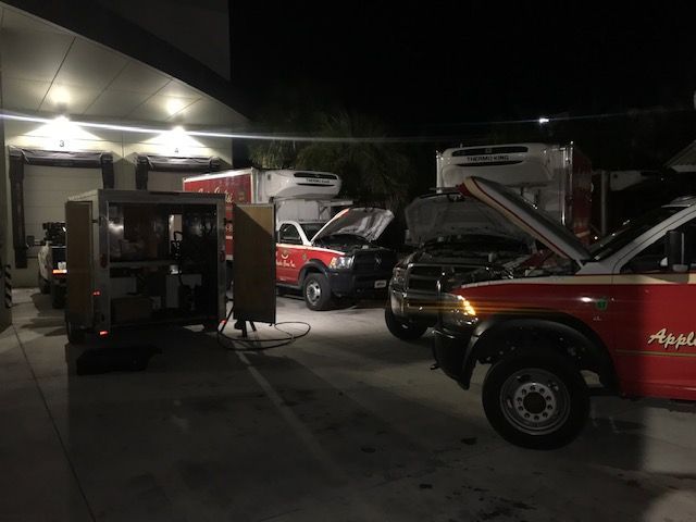 Night shot of several trucks with open hoods at a loading dock, possibly being serviced.