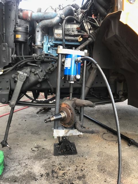 A truck front axle assembly being worked on with a hydraulic press.