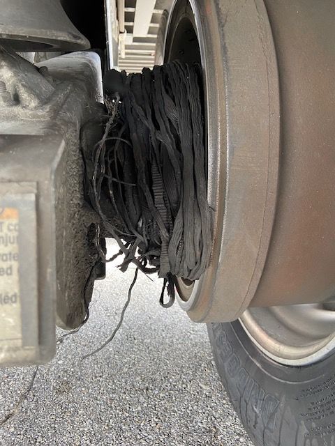 Close-up of a damaged truck component, black debris wrapped around metal parts.