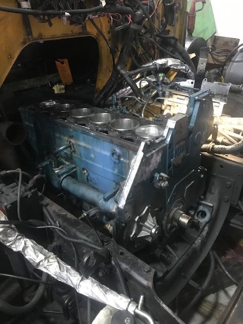 Blue engine block in a vehicle chassis, likely in a repair shop.