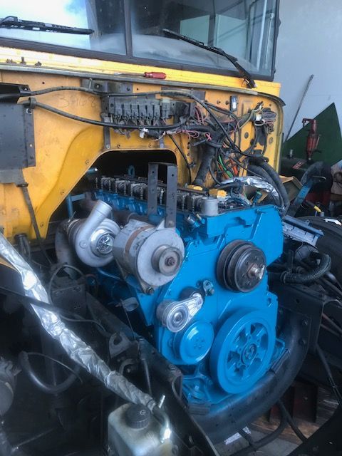 Blue engine in a yellow vehicle, partially disassembled, with visible wiring and turbochargers.