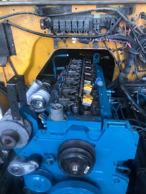 Blue engine with exposed components, viewed from above, in a vehicle's engine bay. Yellow surrounding.