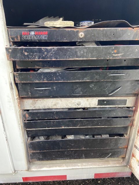 Black metal toolbox with multiple drawers, inside a white container.