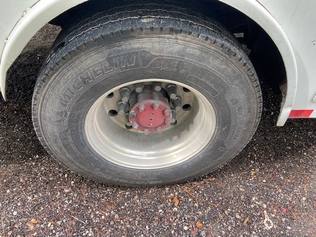 Michelin truck tire on a silver wheel, with a red hub cap, on a white vehicle.