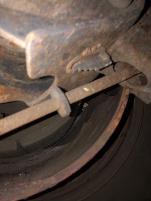 Rusty brake parts with a metal rod attached.