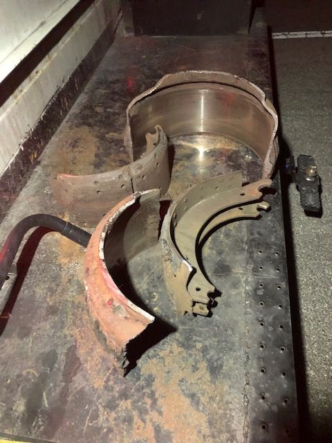 Damaged vehicle brake parts scattered on a metal surface, showing wear and tear.