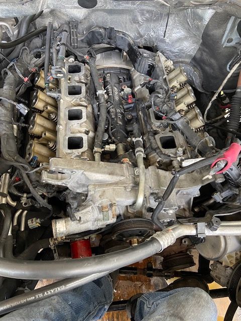 Top-down view of a dismantled car engine with exposed components and tubing.