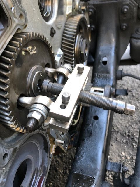 A gear puller tool is removing a gear from an engine block.