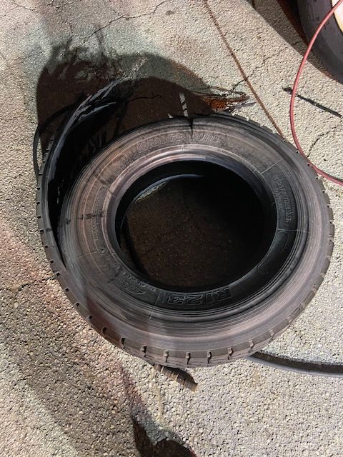 A shredded black tire lying on a concrete surface, with its inner tube exposed.